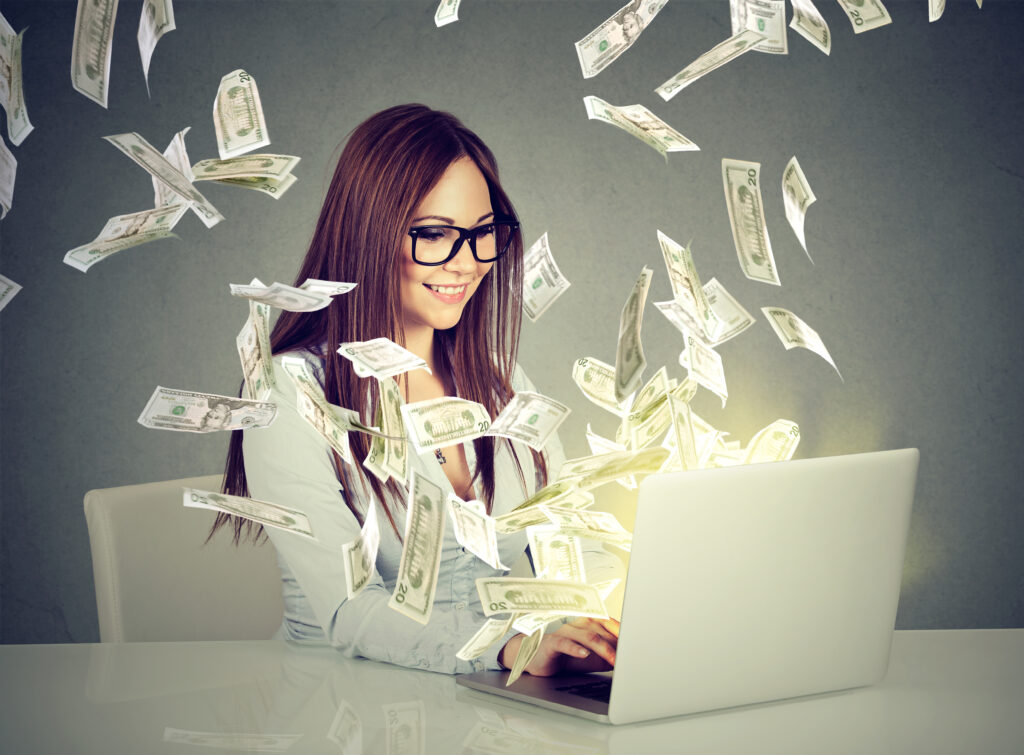 woman using laptop surrounded by money. 